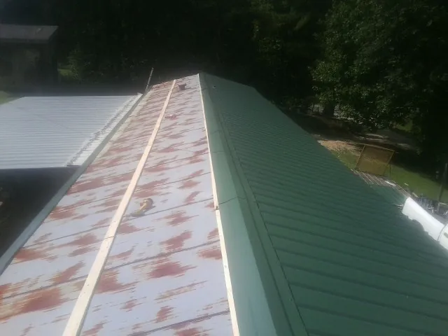 Old rusted panels beside newly installed green metal roofing — Wind Damage Roof Repair by Roofing Brothers in Boonton