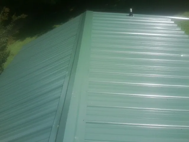 New green metal panels meeting at the ridge of a roof — Flat Roof Repair work by our crew in Boonton