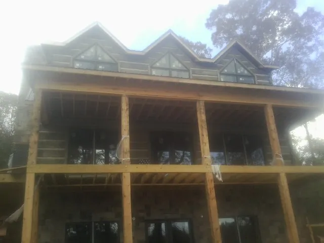 Dormers and porch framing on a large log home under construction — Roof Coating work by our crew in Boonton