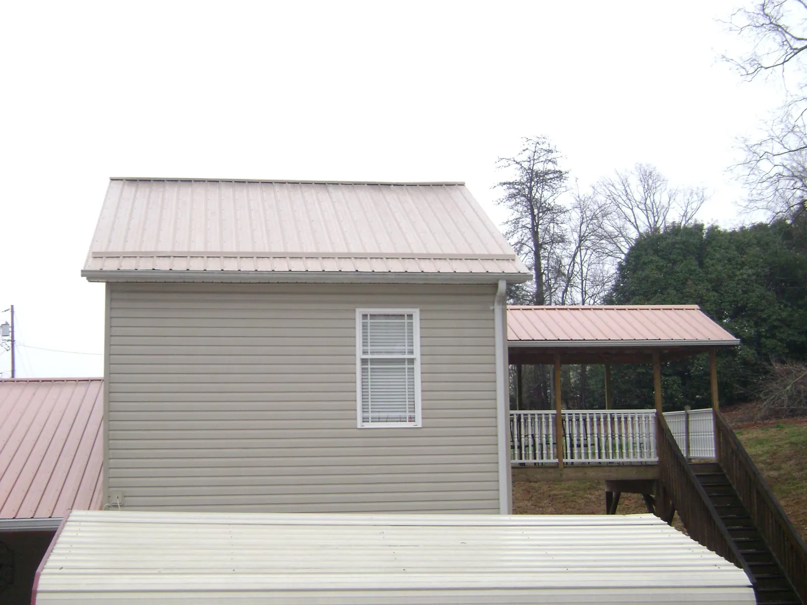 Tan metal roofs on a two story addition and attached porch, from a Roof Replacement job in Boonton