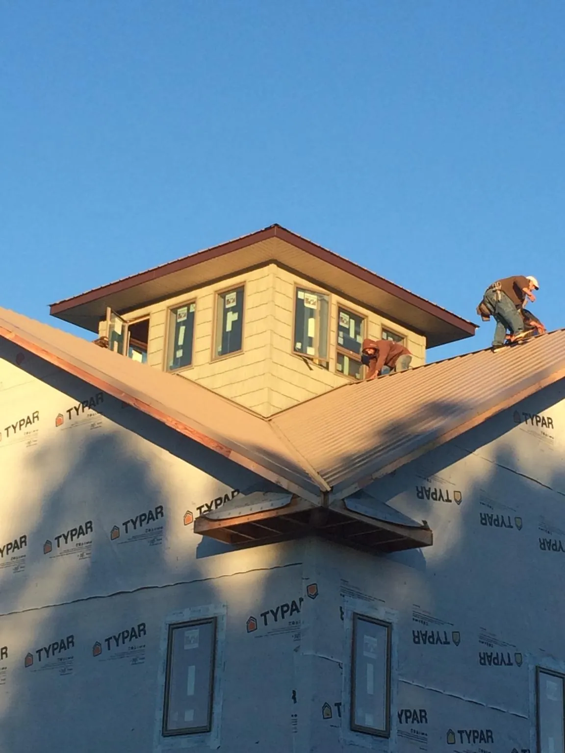 Roofers working around a rooftop cupola on a new metal roof at sunset — Roof Waterproofing in Boonton by Roofing Brothers